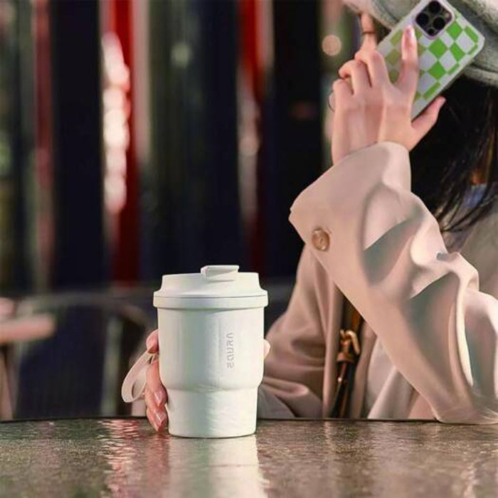 Person holding a white Lepresso Thermo Brew Insulated Tumbler with a blurred background