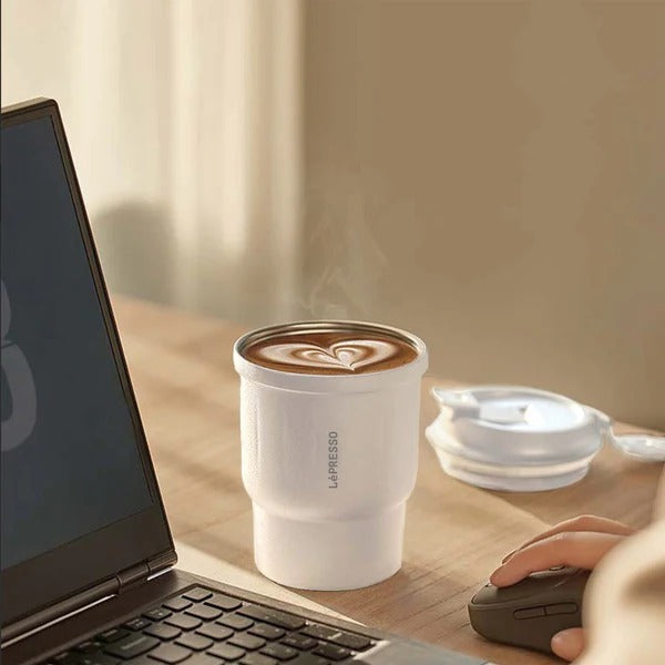 A fresh latte fills the 450ml LEPRESSO Thermo Brew Insulated Tumbler. To the left is a sleek black laptop,