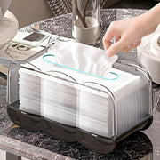 A person takes a tissue from a transparent tissue box on a marble table with their hand.