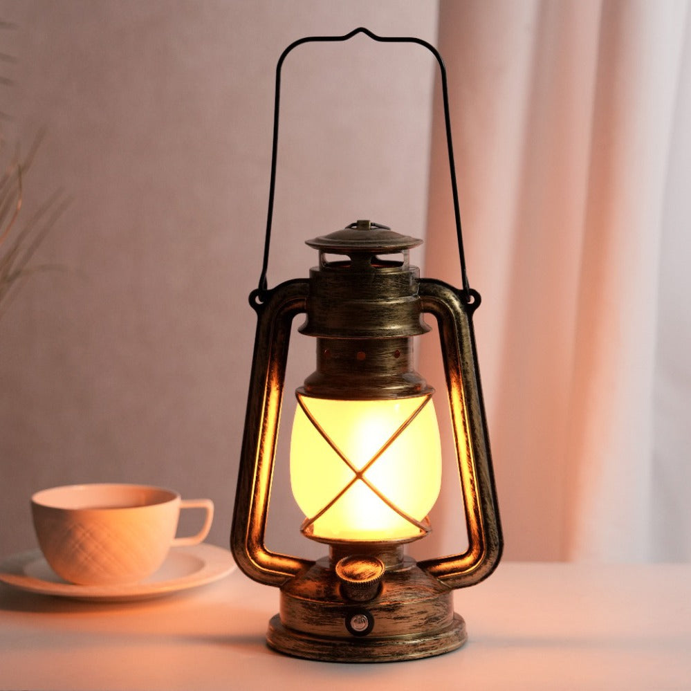 Vintage-style lantern with a warm glow on a table next to a cup and saucer.