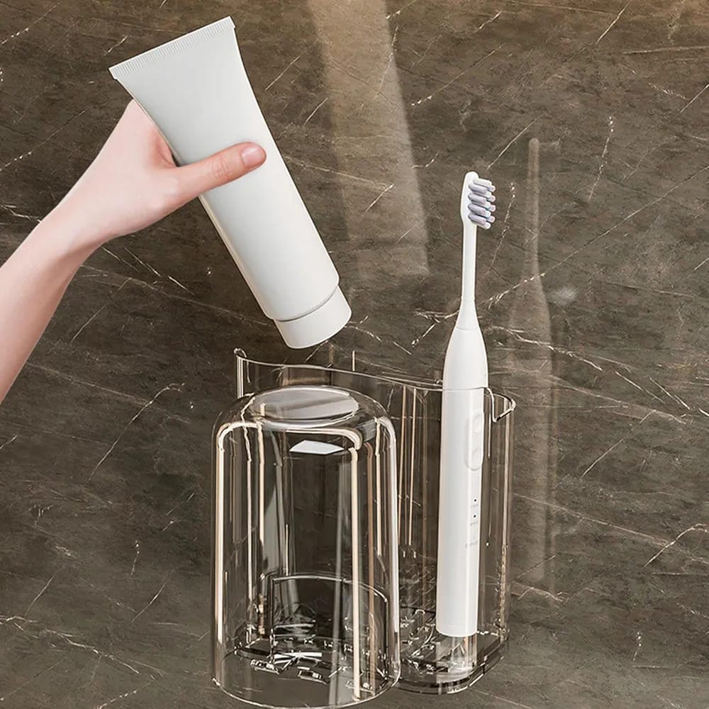 A Person is Taking Toothpaste From Wall Mounted Toothbrush Holder Stand.