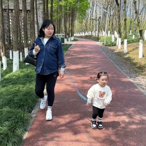 A parent and a child walking in a track with their hands tied to each other using  Child Safety Harness Leash
