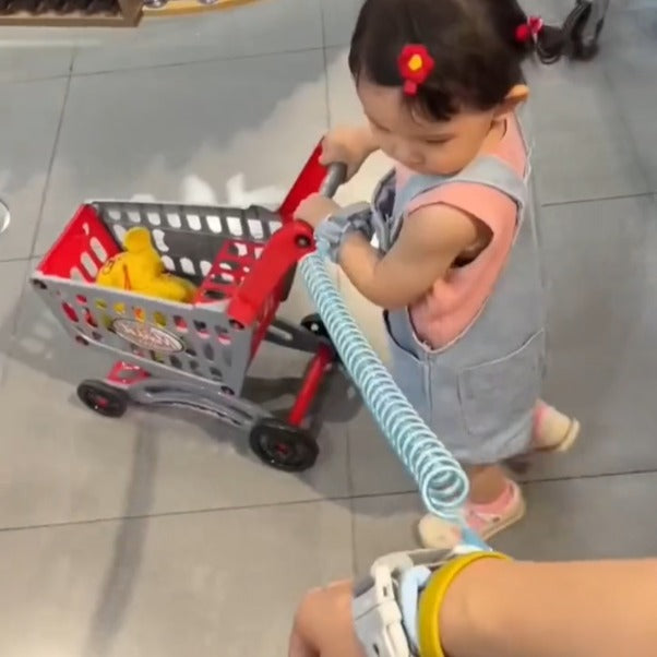 A child holding a trolley by hand tied with Child Safety Harness Leash