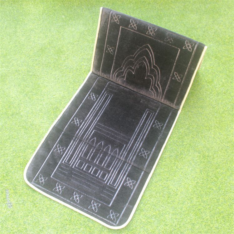 Black color Islamic Foldable Prayer Mat placed on a grass with backrest opened