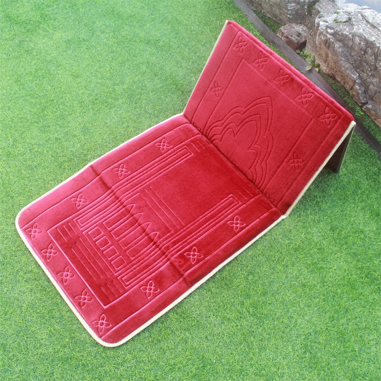 Red color Islamic Foldable Prayer Mat placed on a grass with backrest opened