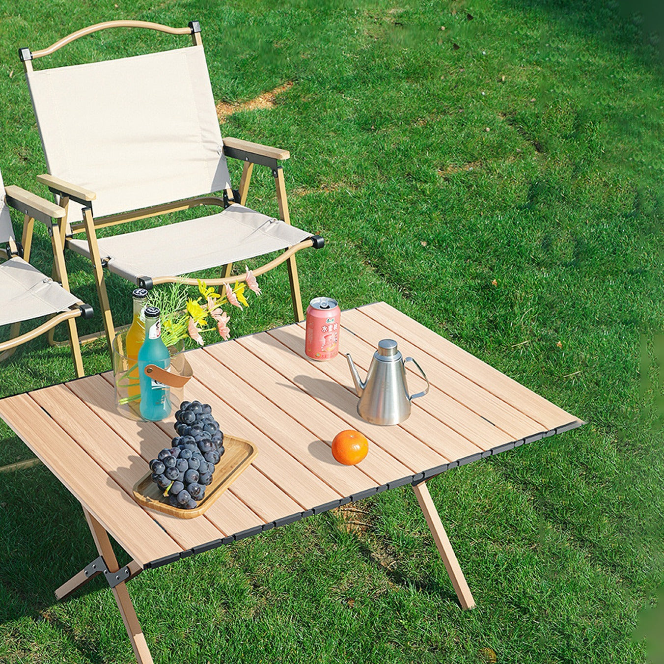 Image displaying Outdoor Portable Camping Table being used on a picnic and some fruits,soft drinks and a jug placed on top of it