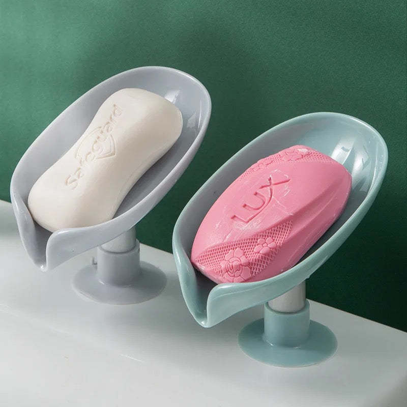 Two Leaf Shaped Soap Holders with soap placed on a surface 