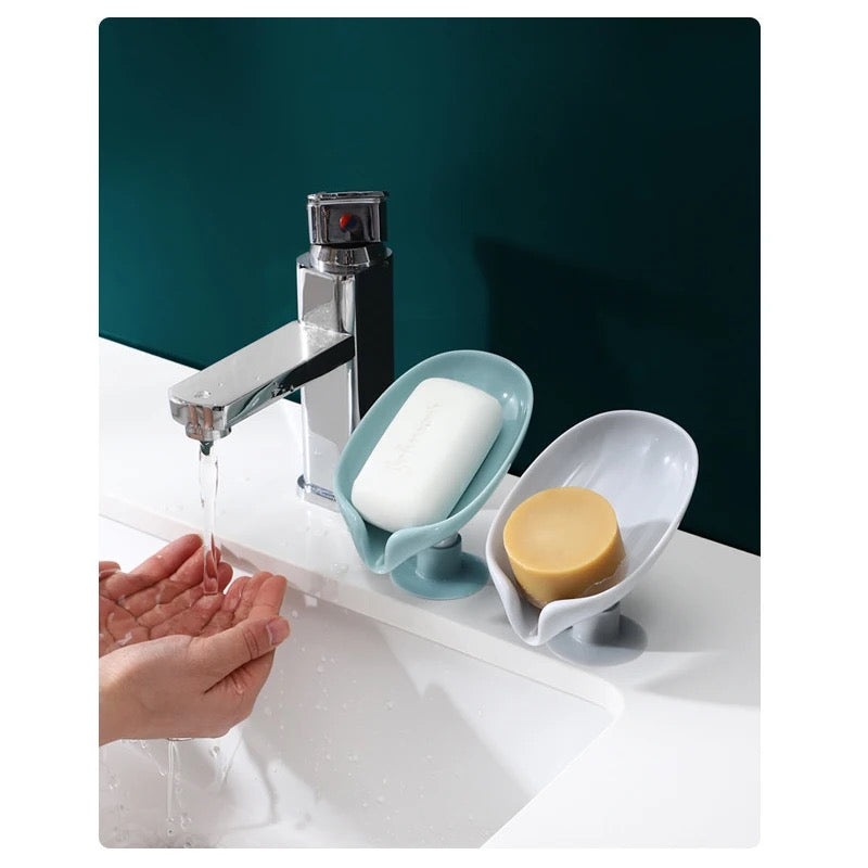 Two Leaf Shaped Soap Holders placed beside to a faucet on a wash basin
