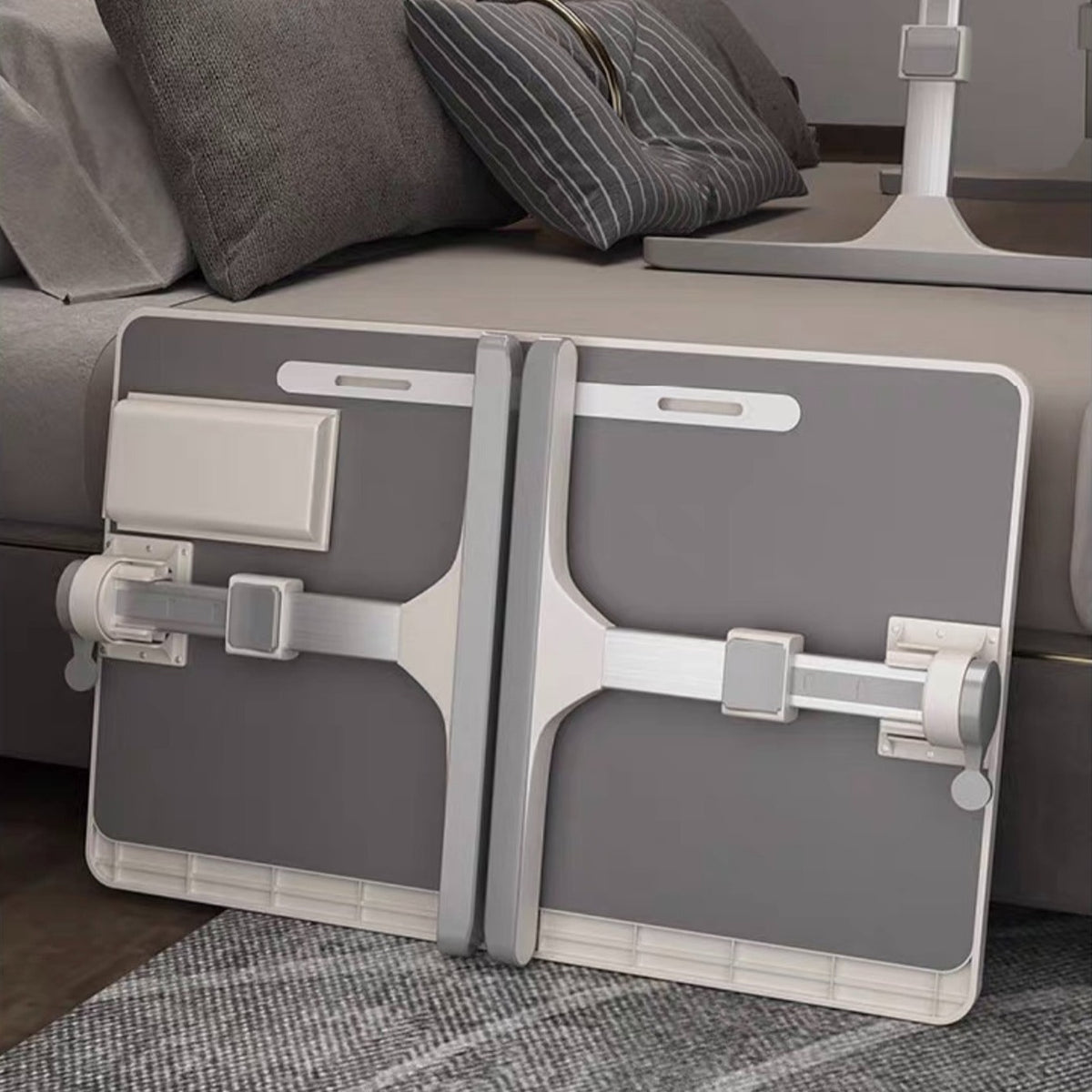 A gray and white Foldable Lifting laptop, study table placed next to a bed