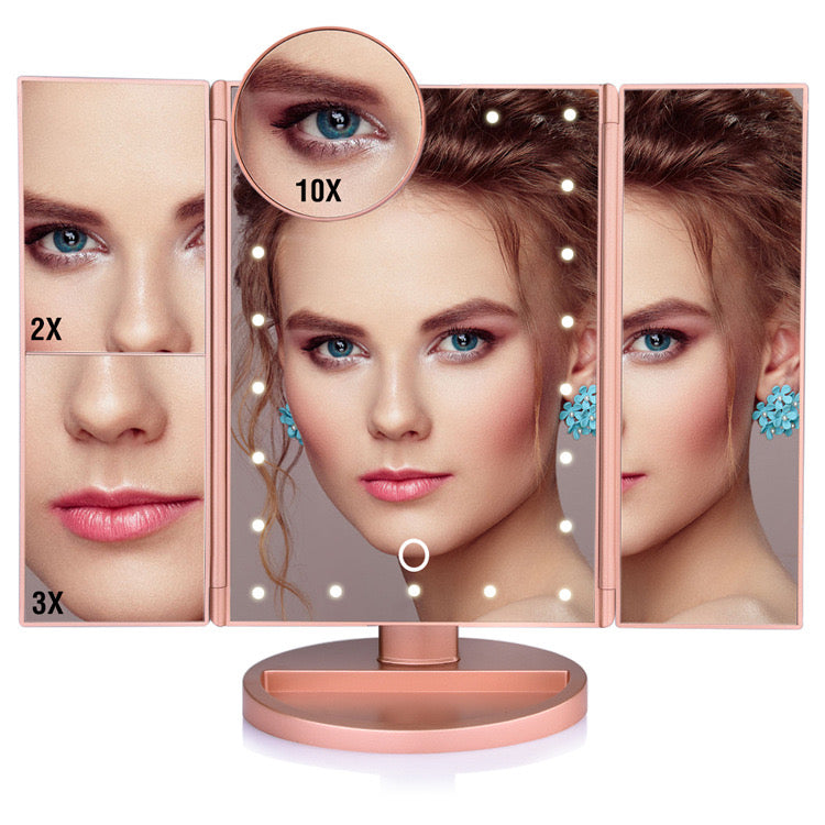 A woman gazes into a tri-fold makeup mirror with LED lights