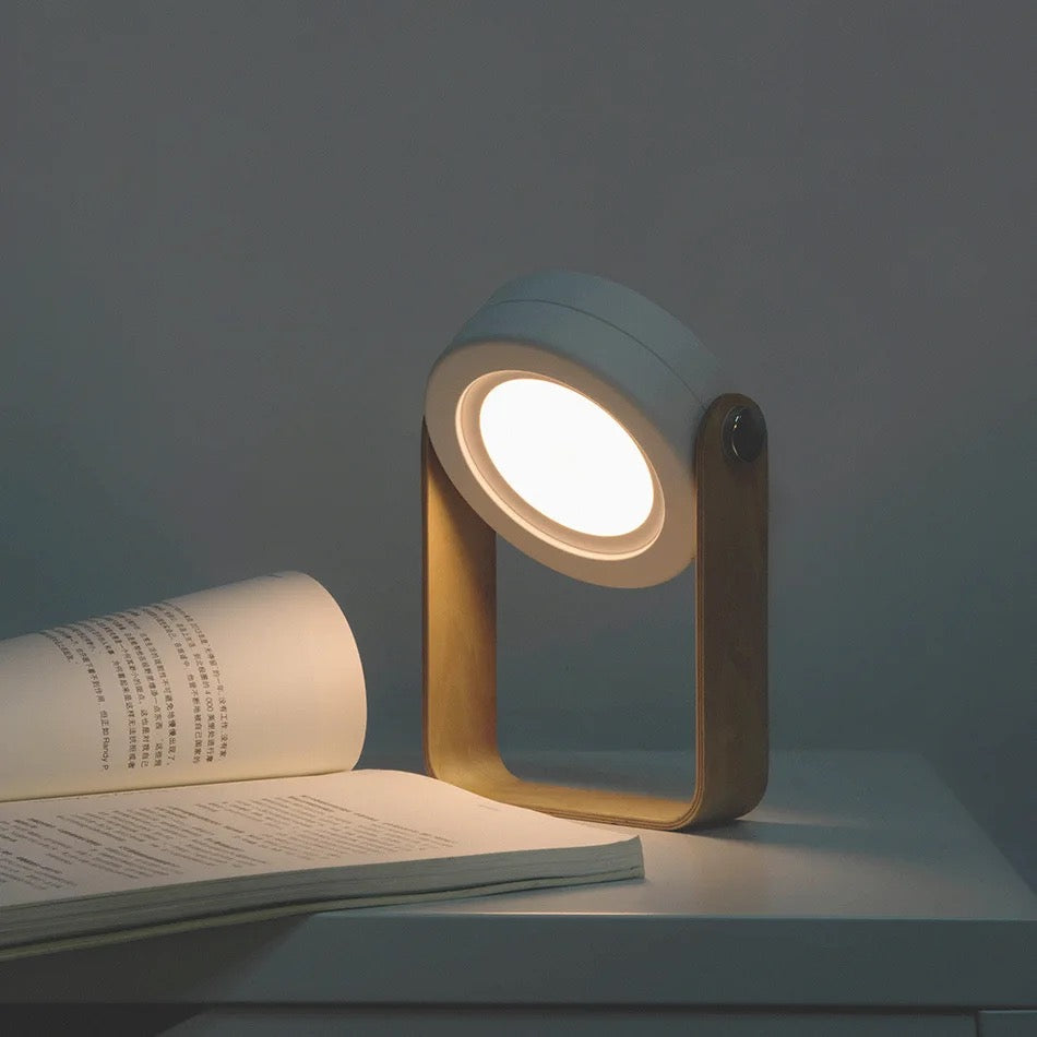 Retractable Table Lamp with USB Rechargeable placed on the table  next to a book