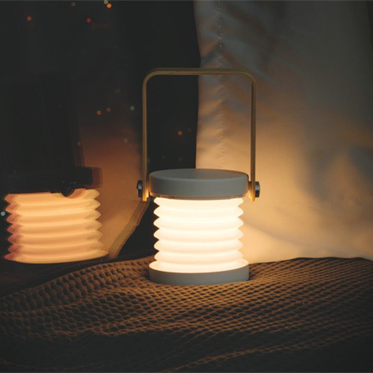 Retractable Table Lamp with USB Rechargeable, on a bed, giving off a warm glow