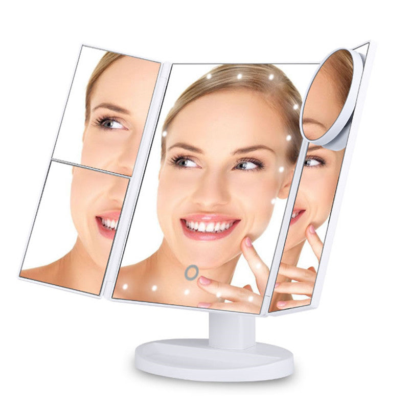 A woman happily holds a tri-fold makeup mirror with LED lights, reflecting her smile