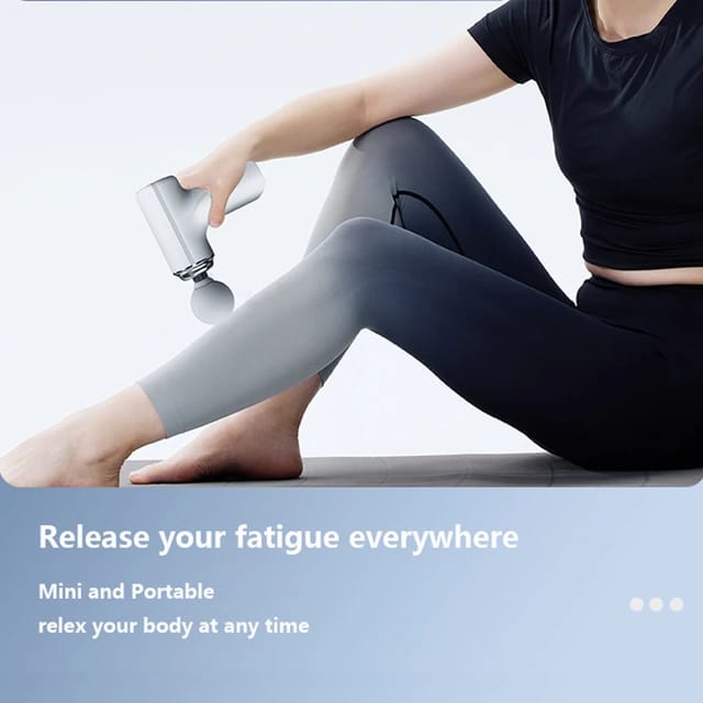 A woman is using a small massage gun to relax her muscles and relieve fatigue