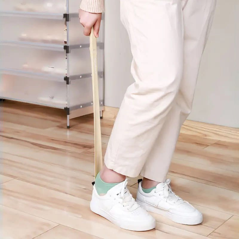 A Person is Wearing Shoe Using Long Handle Shoe Horn.