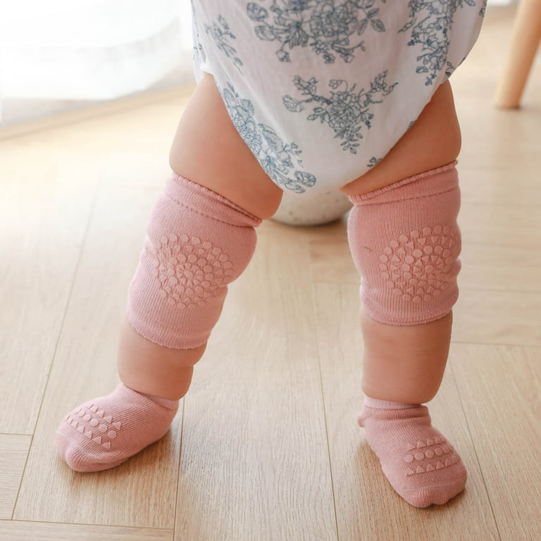 Baby's elbows protected with padded socks while playing on hardwood floor.