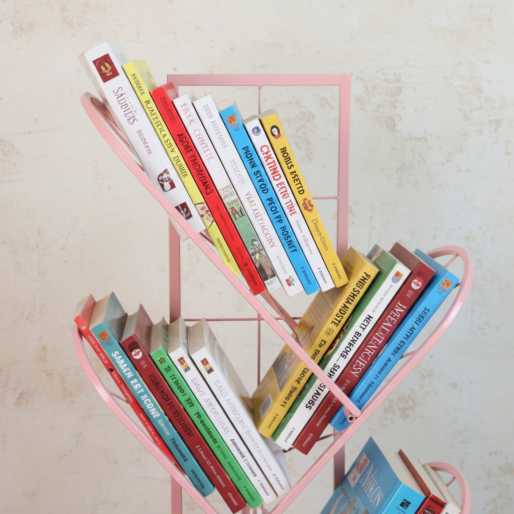 Pink metal bookshelf with books of various colors on a light beige background