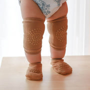 Baby wearing brown knee pads with cushioning for crawling safety.
