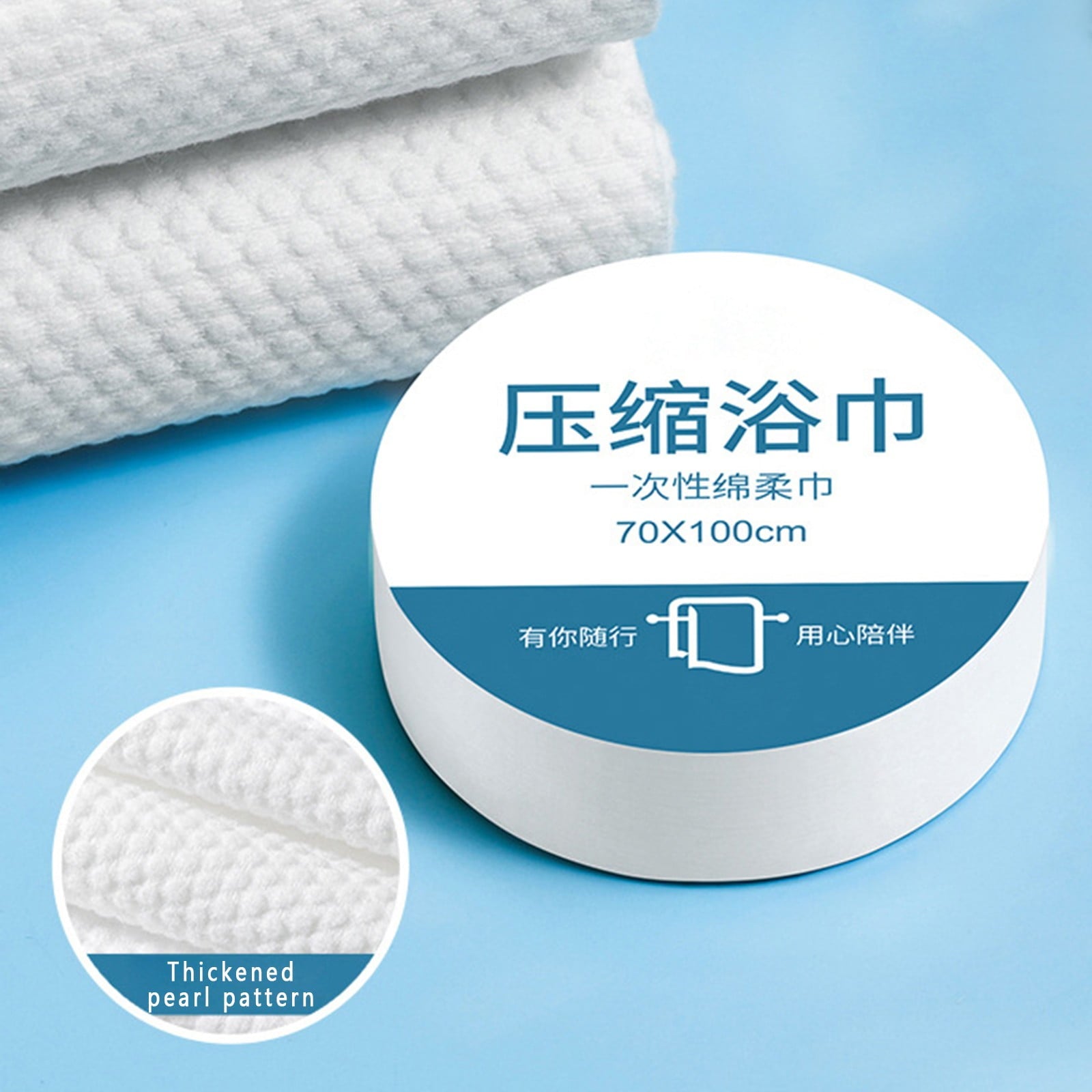 White compressed bath towel with Chinese text on the label, shown alongside a circular inset highlighting its thickened pearl texture, set against a light blue background.