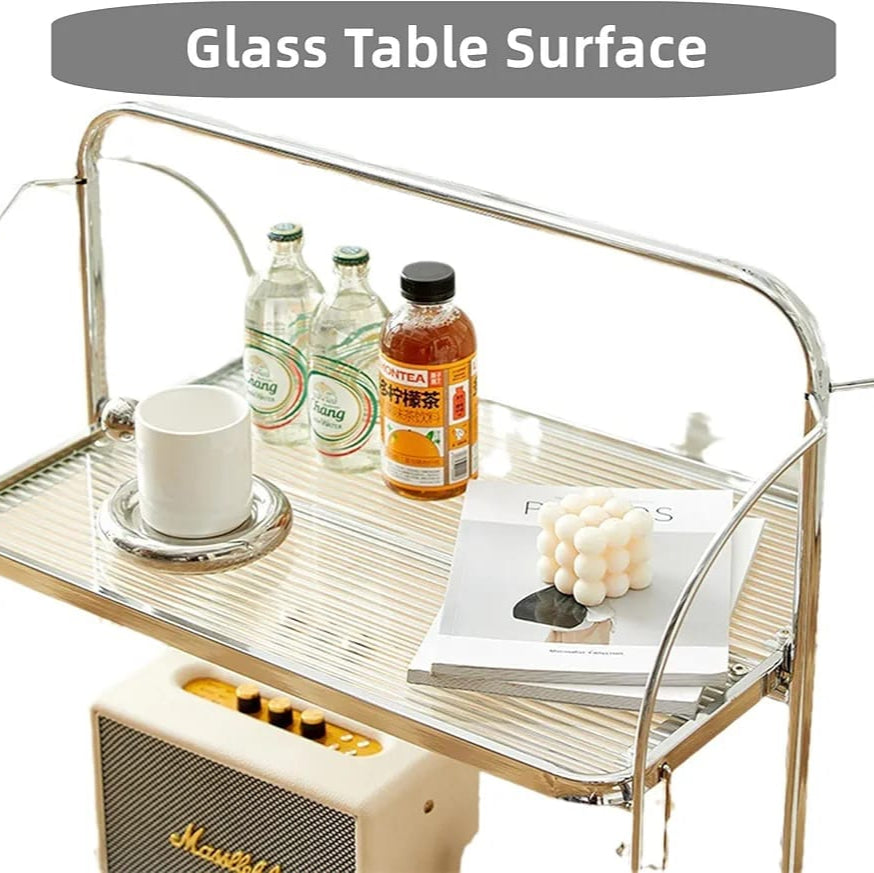  folding 2-tier serving trolley with a chrome finish, glass shelves with food items.