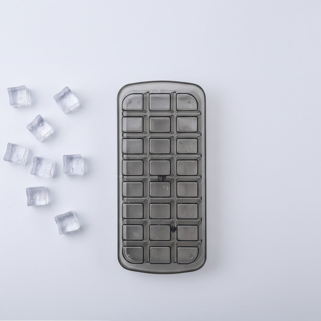 Gray ice cube tray with small ice cubes on a light gray background