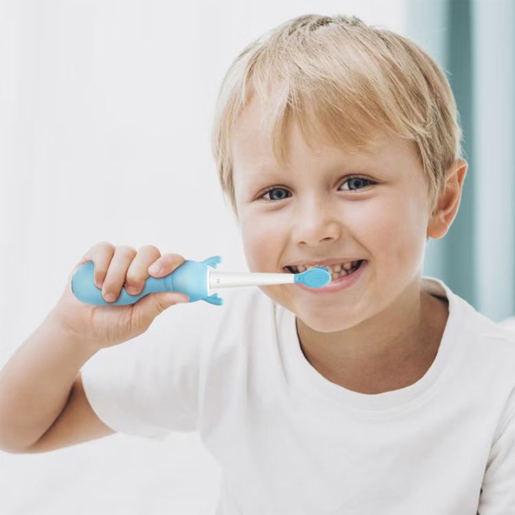 Smiling young boy brushing his teeth with a blue kids electric toothbrush, promoting fun and effective oral hygiene.