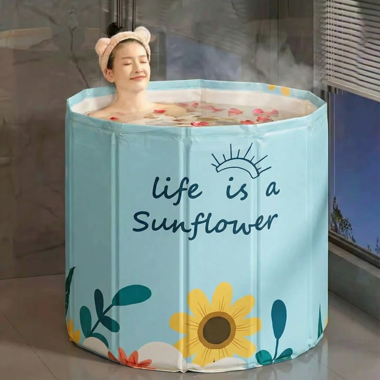 A woman is relaxing in a light blue portable adult bathtub.
