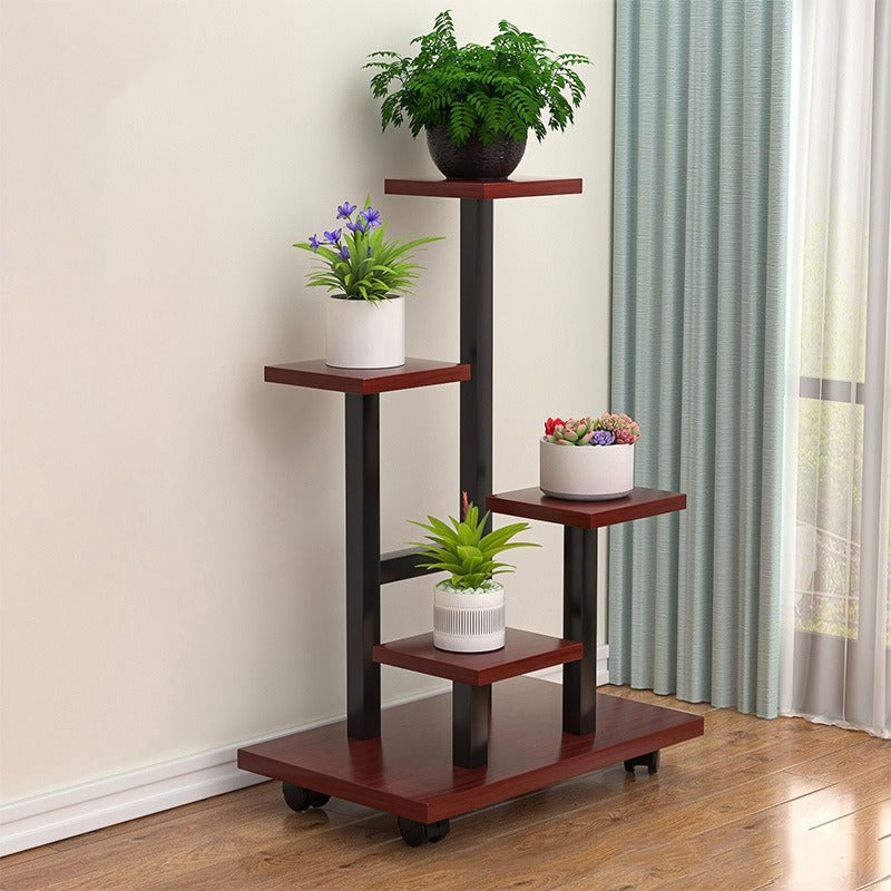 multi-tier indoor plant stand with four staggered shelves displaying different potted plants, placed on wooden flooring beside a window with curtains