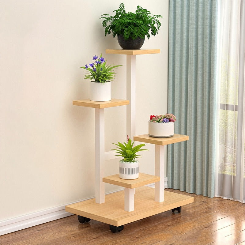 multi-tier indoor plant stand with four staggered shelves displaying different potted plants, placed on wooden flooring beside a window with curtains