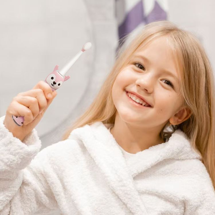 Smiling young girl holding  a pink kids electric toothbrush, promoting fun and effective oral hygiene.