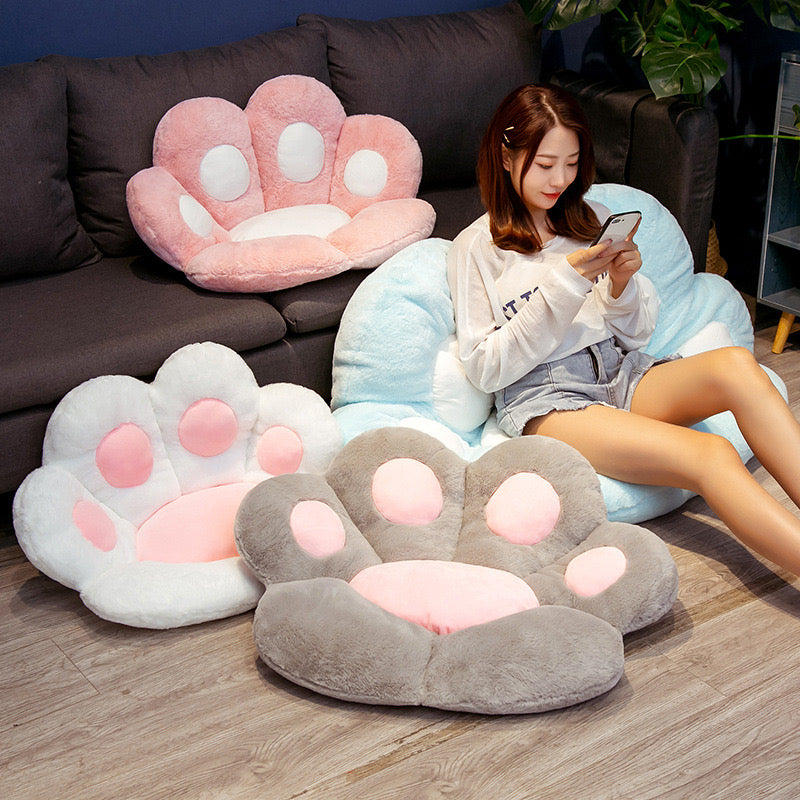 3 small size cat cute paw cushion where 2 on flloor and 1 on sofa and a big size cute cat paw cushion on floor where a women sitting on it