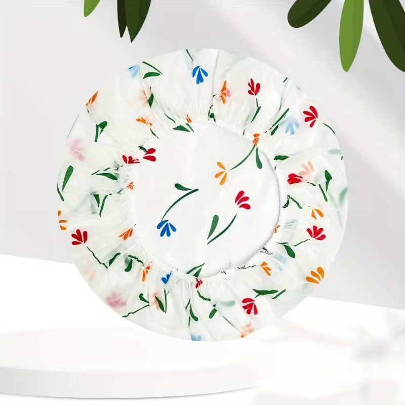 Floral-patterned shower cap on a white background with green leaves.