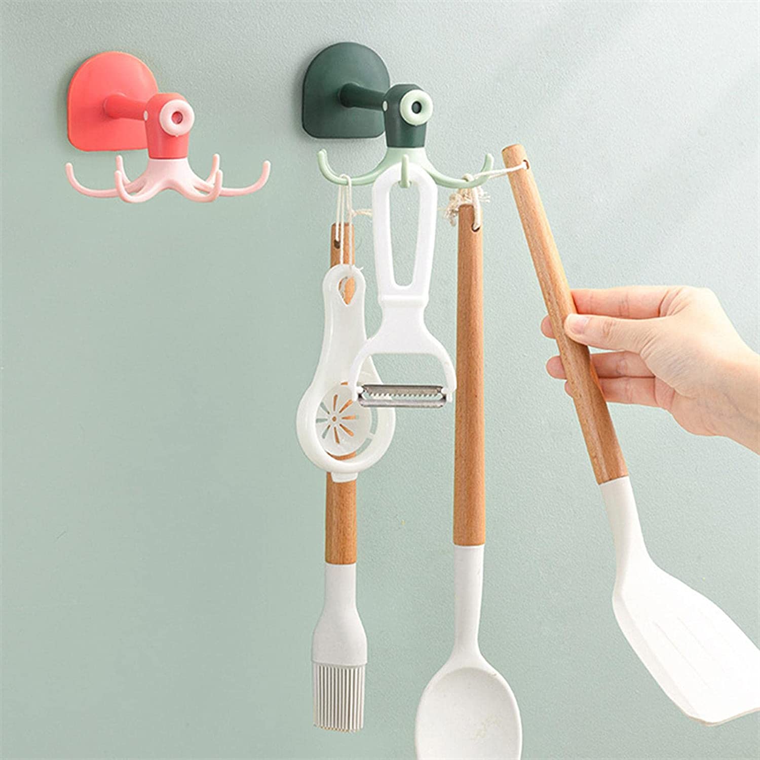 A person holding utensils in front of a Wall Mount Octopus Hook, ready to hang them up.