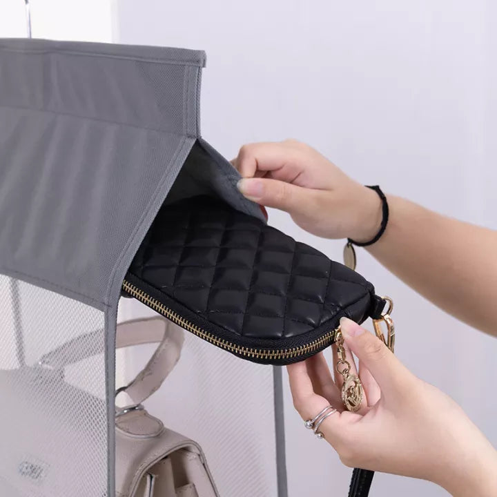 A hand taking a purse from multi layer hanging handbag wardrobe organizer