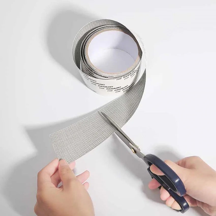 a scissors cutting a Self-adhesive Net Door Holes Repair Mesh Tape 
