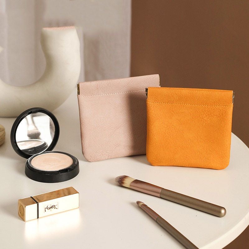 A PU leather retro mouth automatic closure pouch sat on the table next to some items