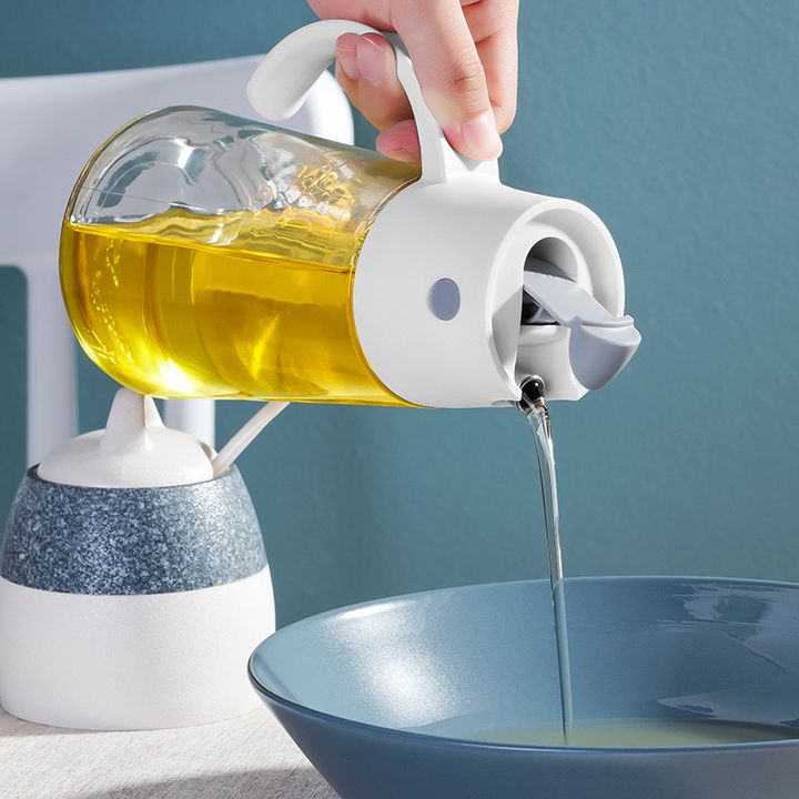 Someone is pouring oil into a pot with the help of a 650ml Capacity Kitchen Automatic Oil Dispenser Bottle