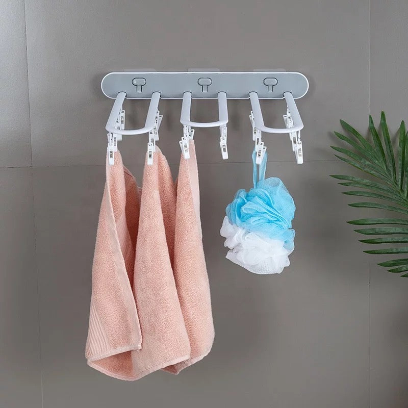 A Folding Drying Rack with Multi-Clips Wall-mount Cloth Hanger displaying three towels hanging on it