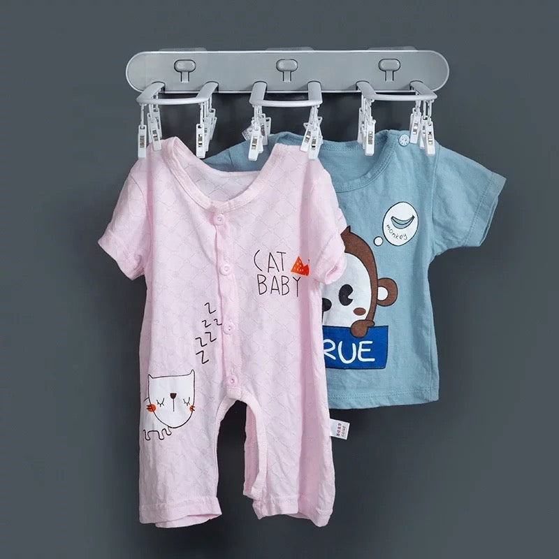 A wall-mounted folding drying rack with multi-clips, displaying neatly hung baby's clothes