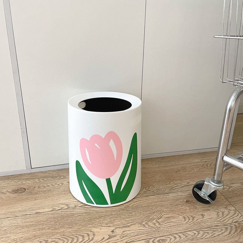 Round shaped Flower Design Home Trash Bin placed beside to a trolly cart in a room