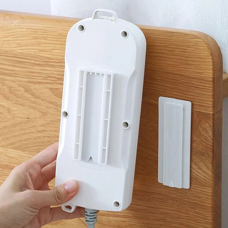 A hand trying to hang socket on Wall Mount Punch Free Socket Holder